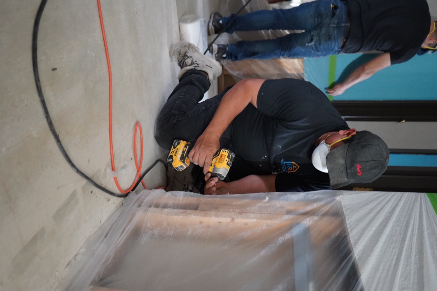 Revive Restoration technician in uniform rebuilding a Michigan home, with the owner's furniture protected in plastic wrap